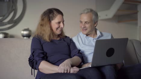 Cheerful-mid-adult-couple-with-laptop-excited-with-new-app